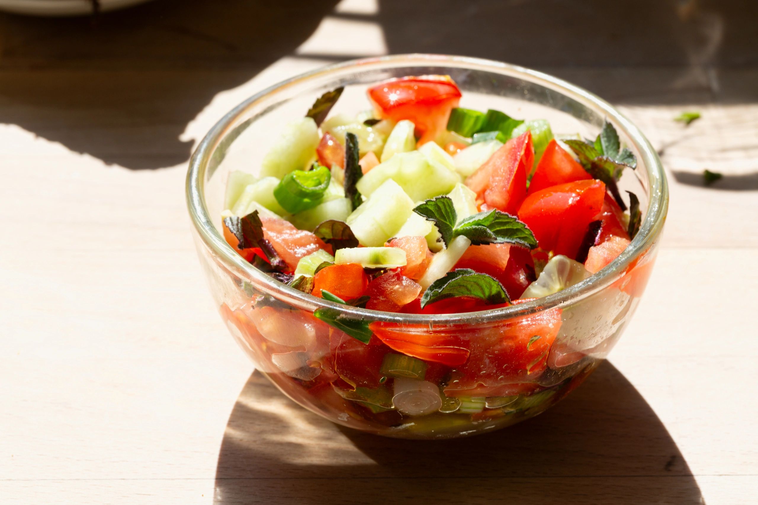 Fresh cucumber and tomato salad in a glass bowl